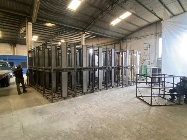 Operario junto a racks metálicos negros en la planta de Racks CCR en Puebla